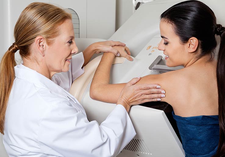Radiographe plaçant le corps d'un patient sur le coussin de mammographie en mousse